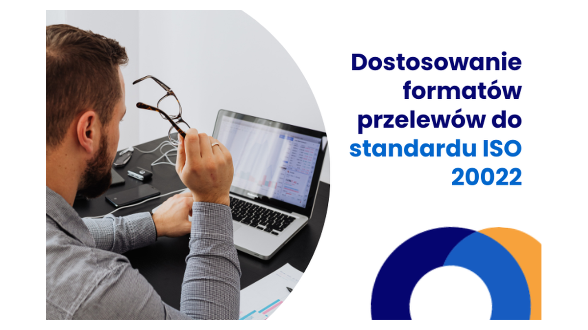 Grafika SaldeoSMART do wpisu o ISO 20022: mężczyzna z okularami w dłoni przed laptopem z otwartym zestawieniem, obok napis „Dostosowanie formatów przelewów do standardu ISO 20022”
